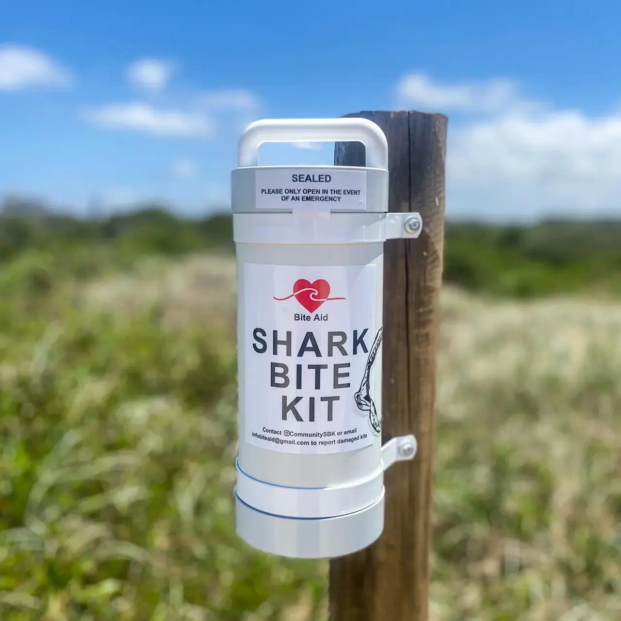 A sealed Shark Bite Kit mounted on a timber post beside a coastal track