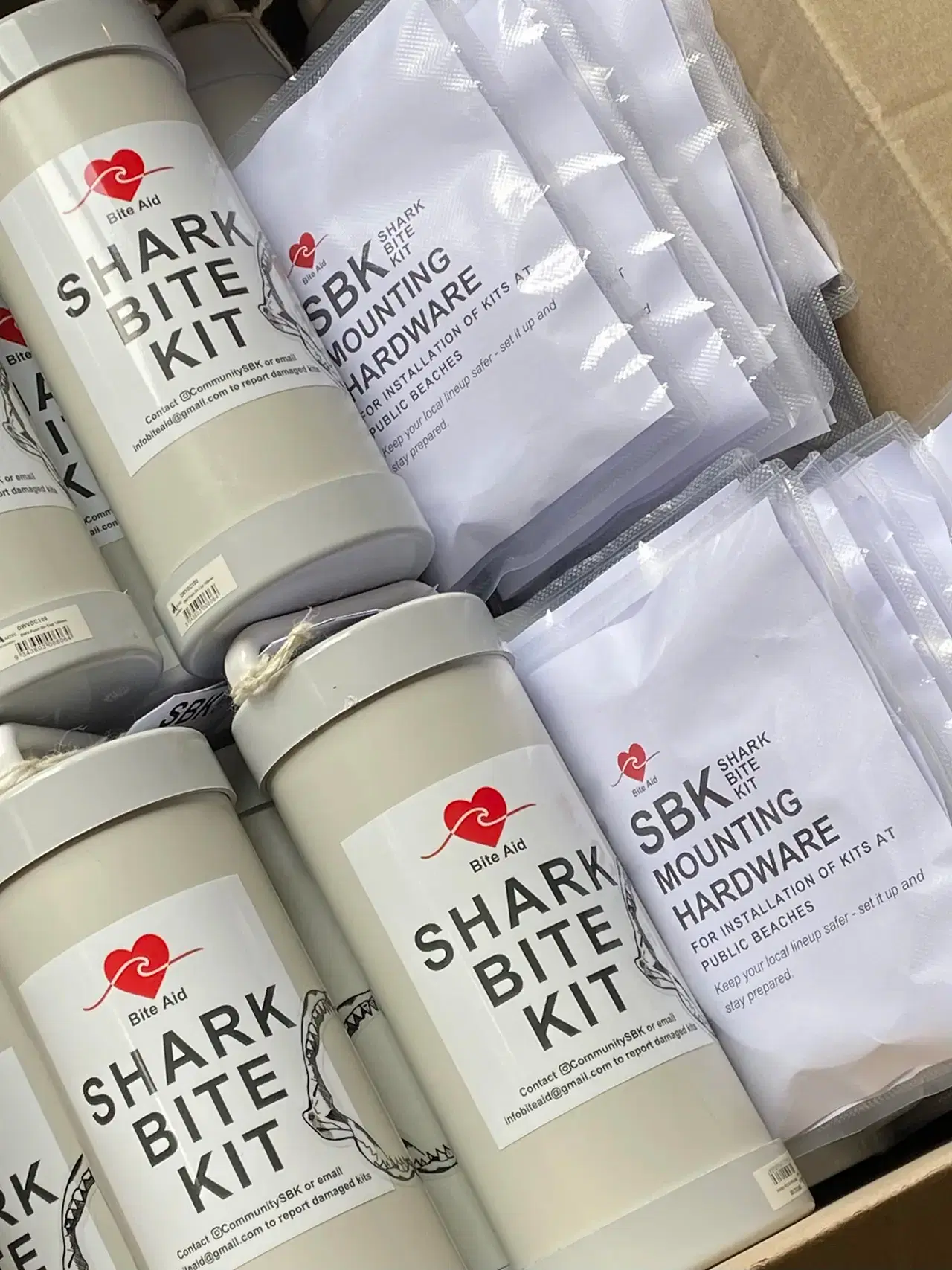 Boxed Shark Bite Kit canisters packed alongside bags of SBK mounting hardware, ready to ship